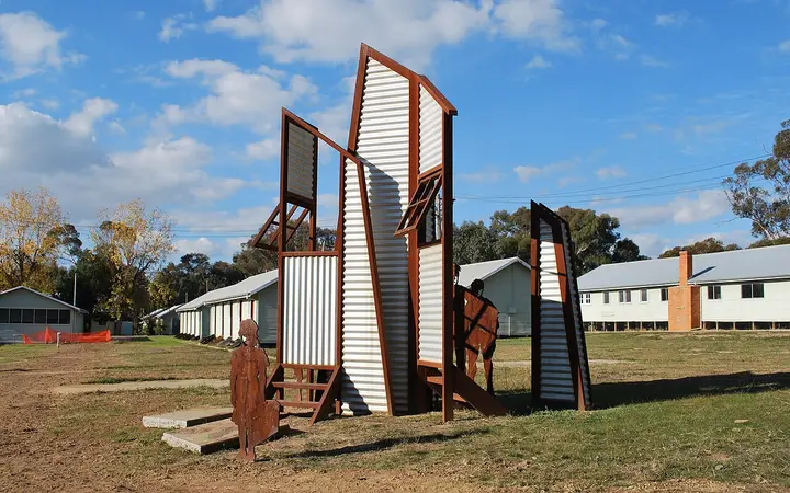 Original huts and sculpture at Bonegilla