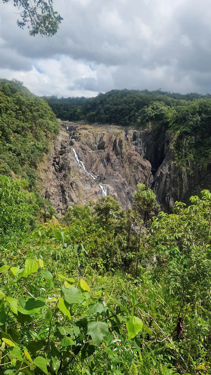 Barron Falls running down the rock walls of the gorge under a cloudy sky