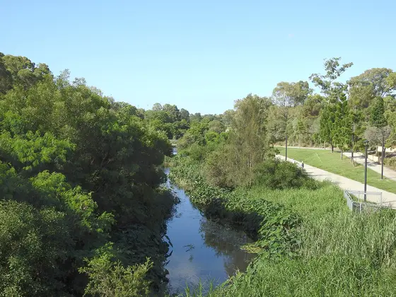 Photograph of Kedron Brook stream, looking downstream from Gympie Road. Shows bicycle and pedestrian path on right. Kedron, Brisbane, Queensland, Australia (Mar